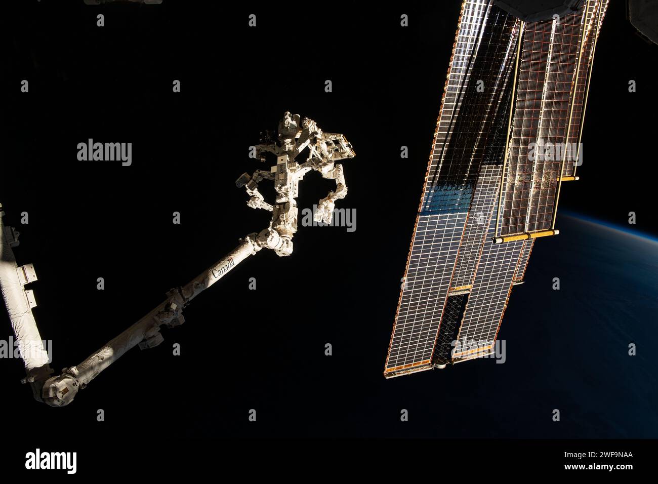 Internationale Raumstation, Erdumlaufbahn. Januar 2024. Der Canadarm2-Roboterarm, links, mit der Dextre-Hand und den wichtigsten Solararrays, die die Sonne reflektieren, während eine Ecke des Erdhorizonts kaum sichtbar ist, während die Internationale Raumstation 261 Meilen über dem Nordosten Chinas in einen Sonnenuntergang in der Umlaufbahn aufsteigt. 2024 in der Erdumlaufbahn. Quelle: NASA Astronaut/NASA/Alamy Live News Stockfoto