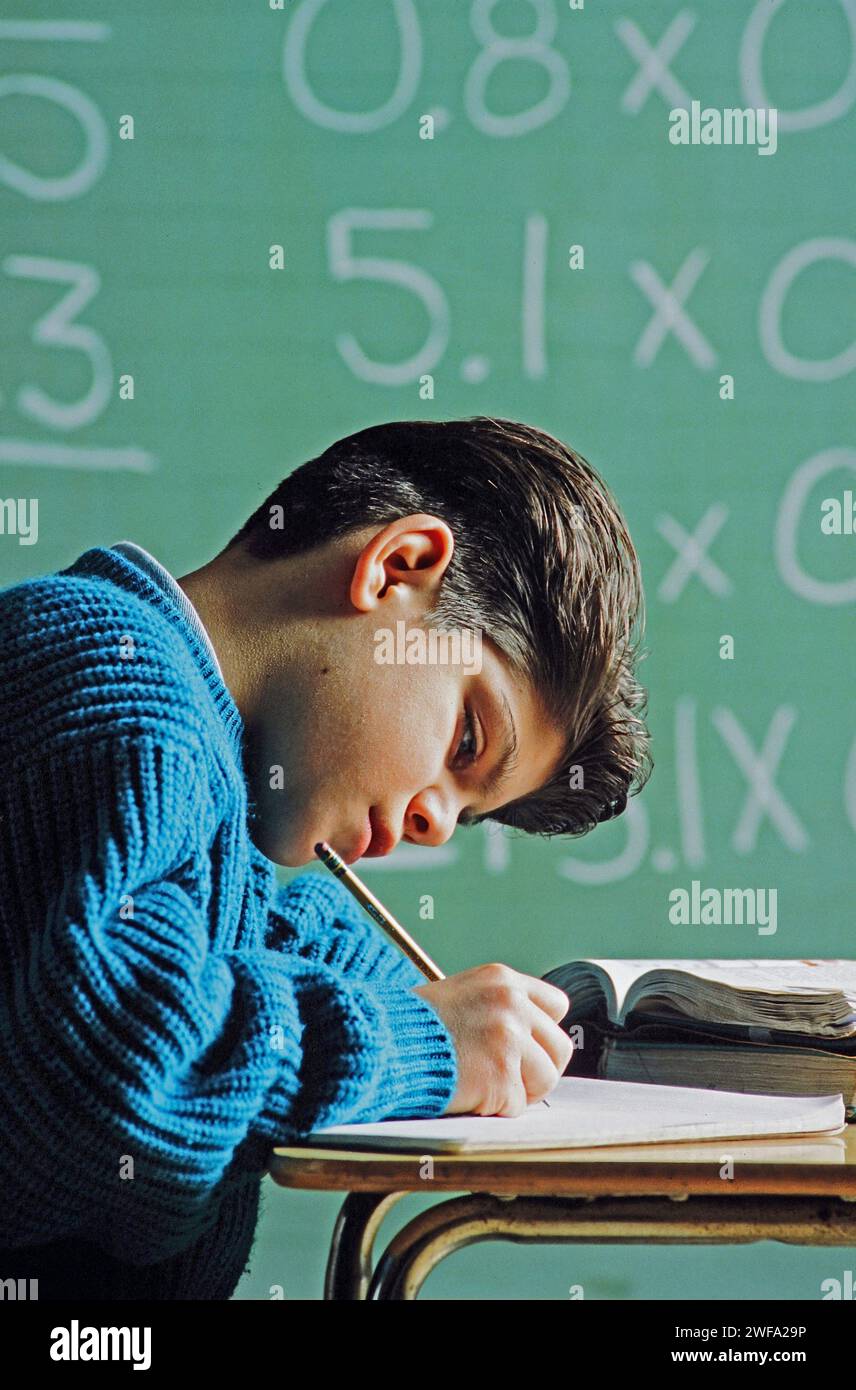 Ein Latino-Schüler, der sich konzentriert und fleißig an seinem Schreibtisch arbeitet und einen mathematischen Auftrag erledigt Stockfoto