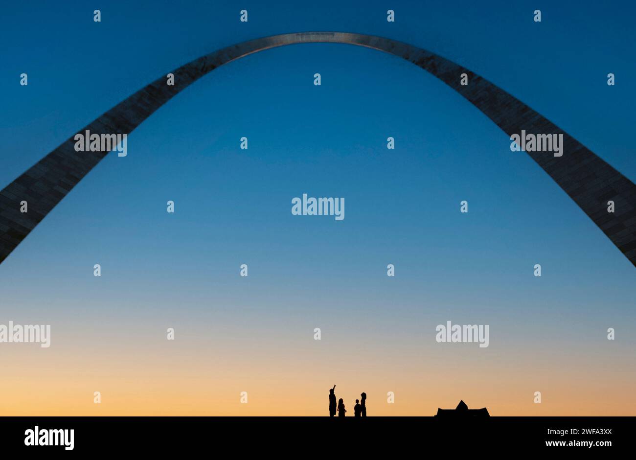 Eine Gruppe von Menschen hat eine Silhouette vor dem Dämmerungshimmel unter dem ikonischen Gateway Arch in St. Louis, Missouri. Stockfoto