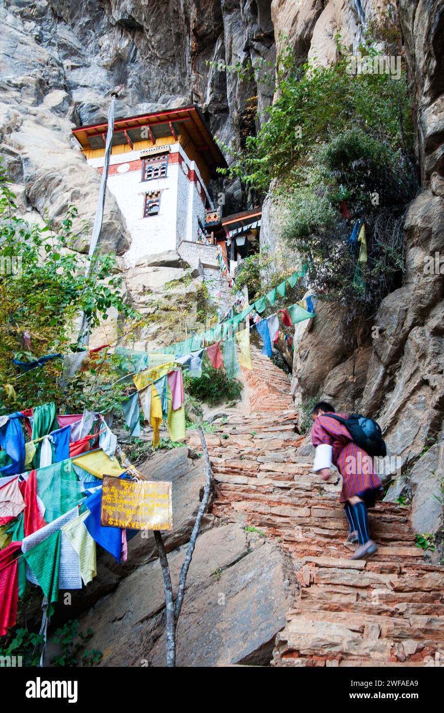 Bhutaner steigen steile Treppen auf dem Weg zum Kloster Tiger's Nest hinauf, vorbei an vielen Gebetsfahnen, die auf dem Weg in der Nähe eines Chortenpfades, Paro Va, aufgereiht sind Stockfoto