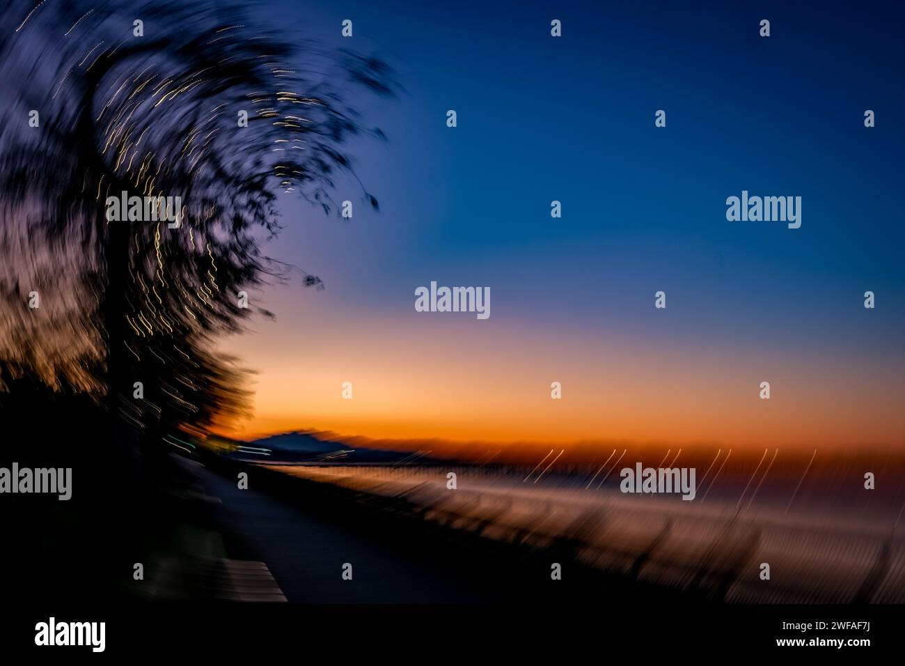 Intent Camera Movement (ICM) erzeugt ein einzigartiges Bild des Sonnenaufgangs in White Rock, BC. Kamerabewegungen verschwimmen Ufer, Pier, Berge und Uferpromenade. Stockfoto