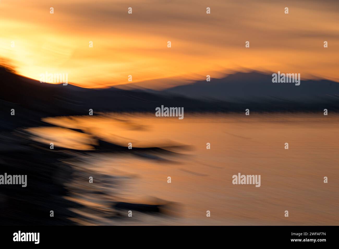 Wenn die Sonne hinter den Bergen auftaucht, ist die wunderschöne Uferpromenade von White Rock von goldenem Licht durchflutet. Intent Camera Movement (ICM) sorgt für Unschärfe. Stockfoto