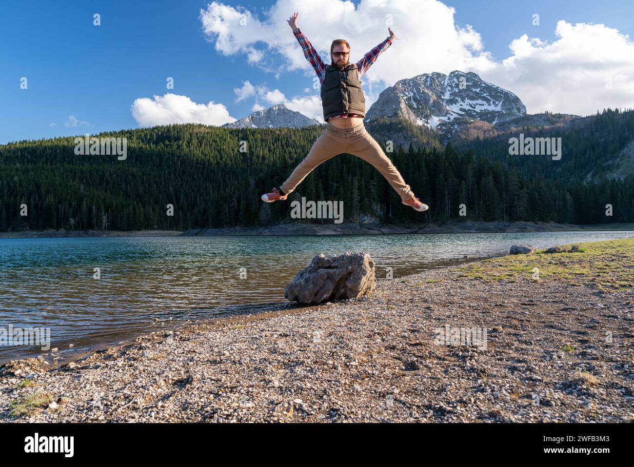 Glücklicher junger bärtiger Mann springt vor Freude in der Natur Stockfoto