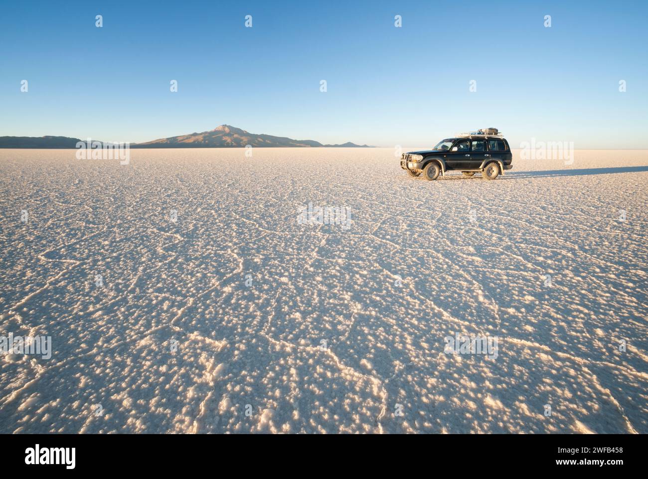 Jeep, der bei Sonnenuntergang über Salzwasser fährt, Salar de Uyuni, Bolivien, Südamerika Stockfoto