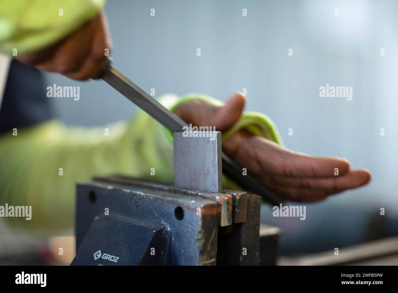 Ein Kaukasier mit grüner Jacke und Schutzbrille benutzt ein elektrisches Werkzeug für ein Holzbearbeitungsprojekt Stockfoto