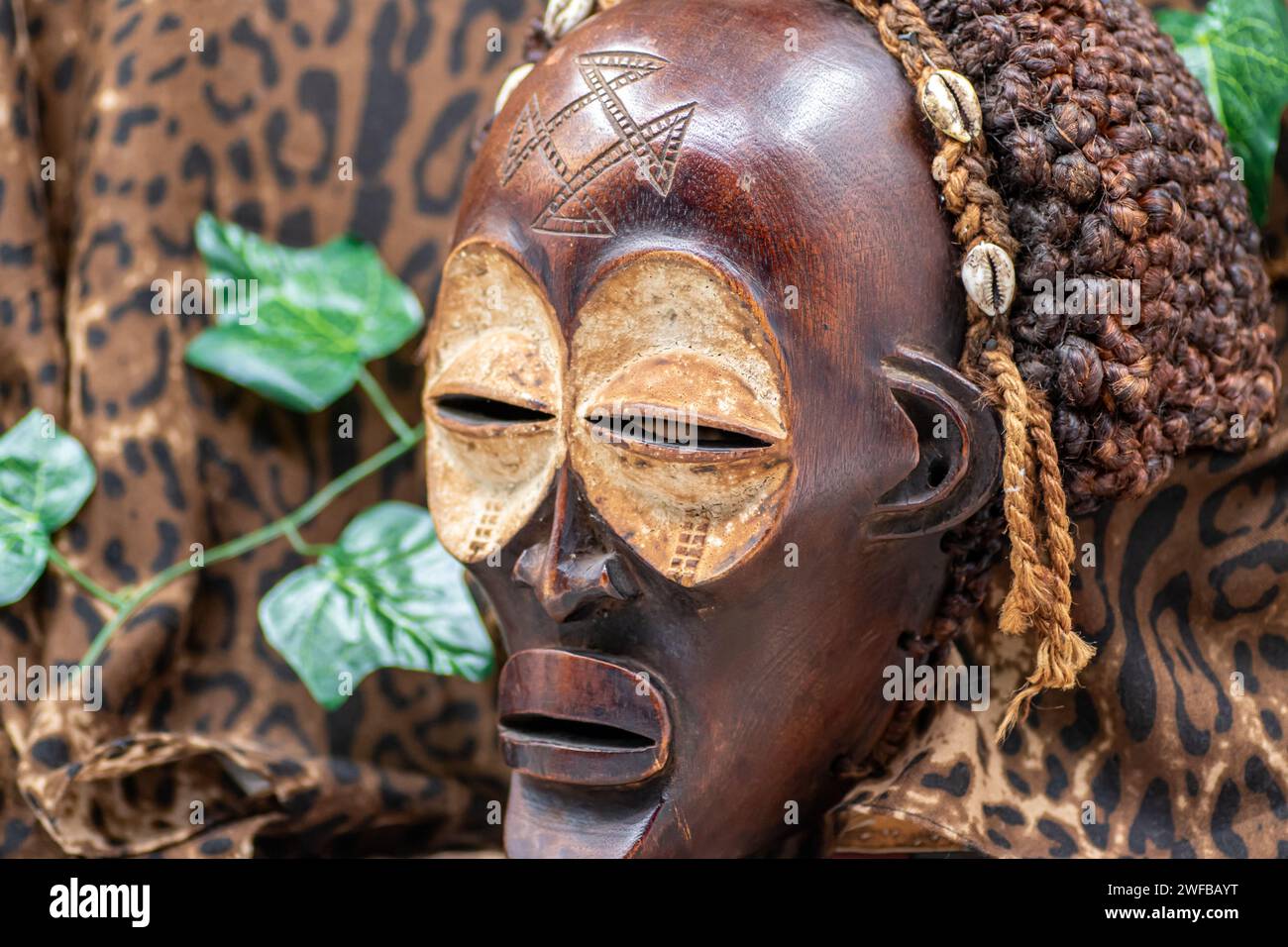 Afrikanische Holzmaske aus Uganda, zum Familien- oder Personenschutz, aus heimischem Holz, Seilen und Muscheln als Haarschmuck Stockfoto