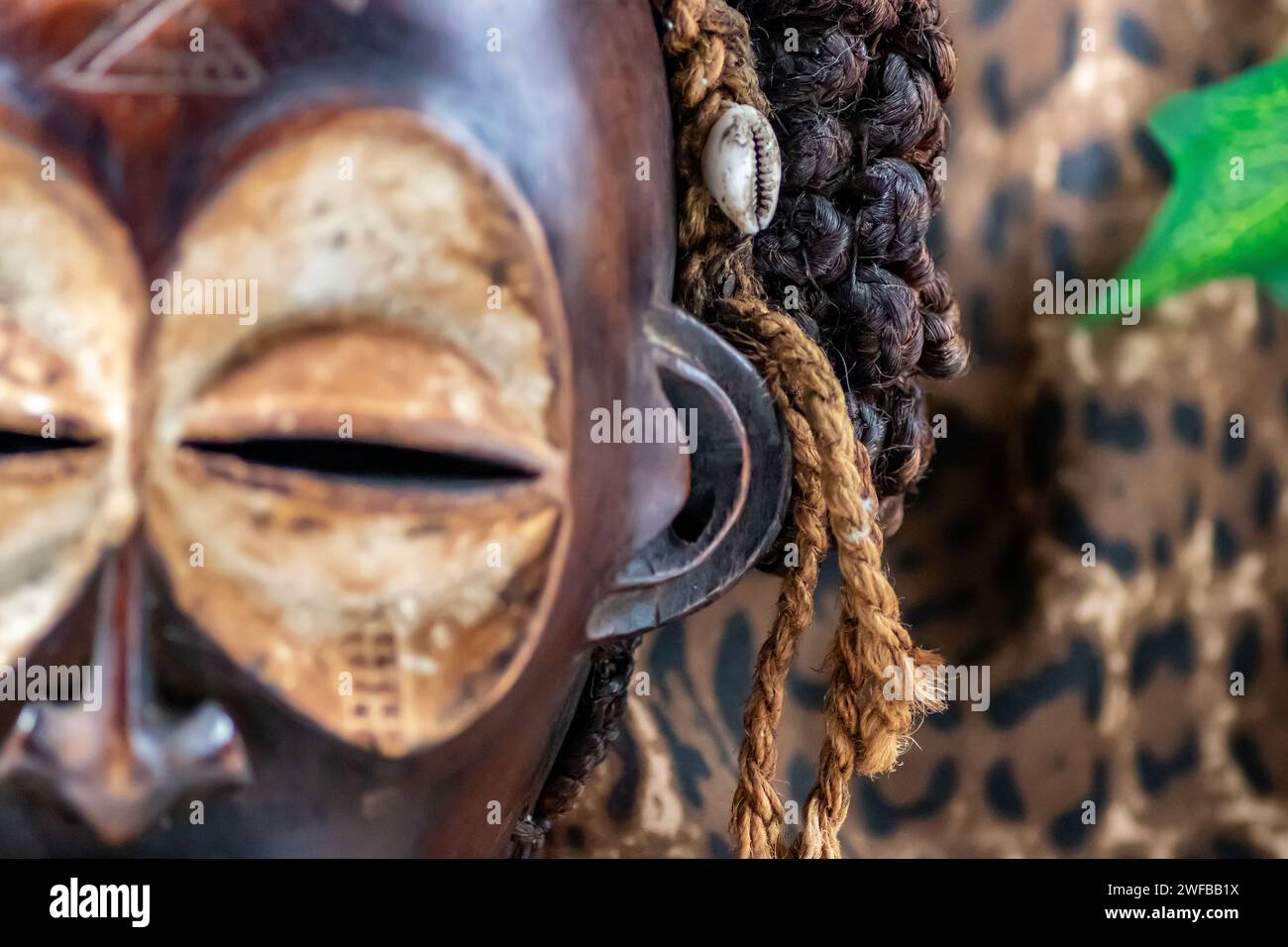 Afrikanische Holzmaske aus Uganda, zum Familien- oder Personenschutz, aus heimischem Holz, Seilen und Muscheln als Haarschmuck Stockfoto