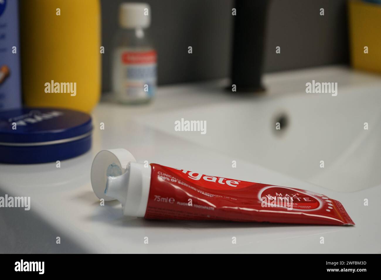 Colgate Max White Luminous Zahnpasta für weißere Zähne rund um die Uhr und Kampf gegen Karies und Zahnstein - Röhre auf einer Badezimmertheke Stockfoto