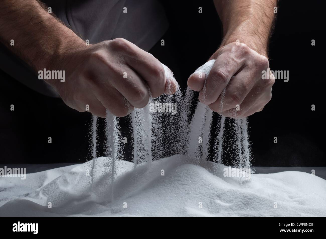 Männer halten Sand in ihren Handflächen und schütten Sandkörner durch ihre Finger. Das Konzept des Lebensflusses Stockfoto