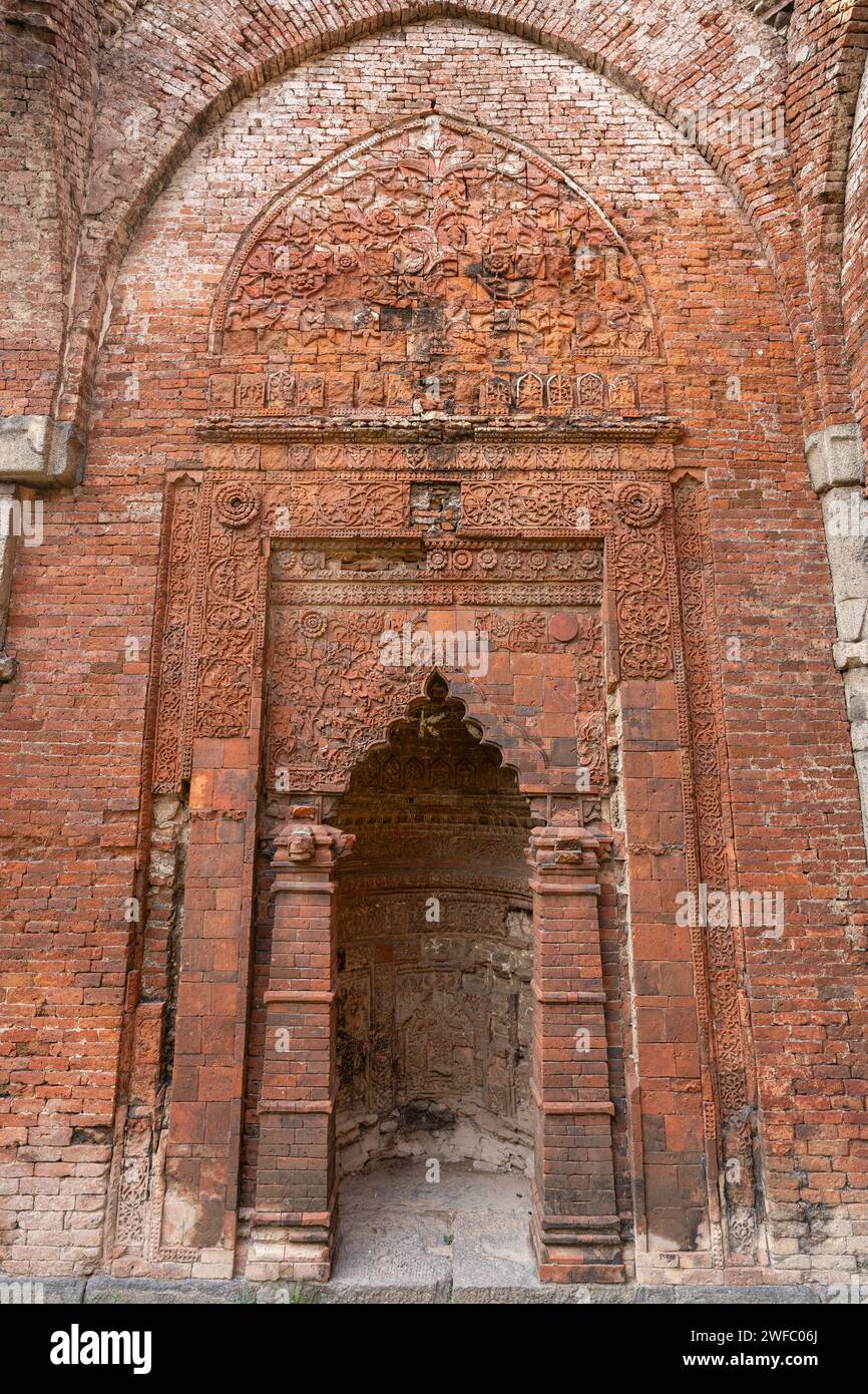 Vertikaler Blick auf den wunderschönen Terrakotta-Mirhab in den Ruinen der antiken Darasbari-Moschee, Shahabazpur, Chapai Nawabganj, Bangladesch Stockfoto