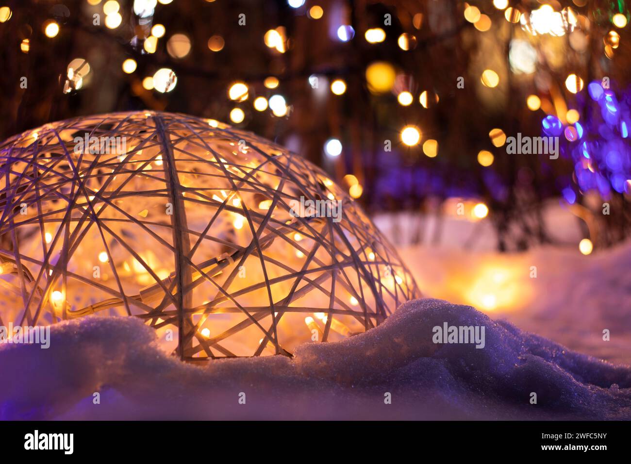 Dekorative Kugel mit Girlanden auf dem Hintergrund von Weihnachtslichtern auf der Straße bei Nacht Stockfoto