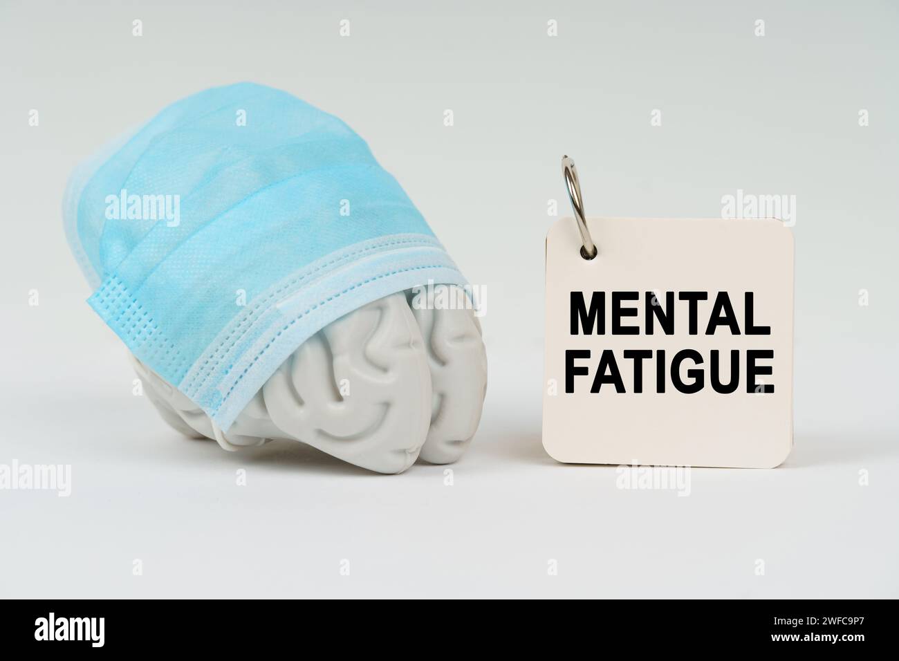Medizinisches Konzept. Auf einer weißen Oberfläche neben dem Gehirn befindet sich ein Notizblock mit der Aufschrift "geistige Ermüdung" Stockfoto