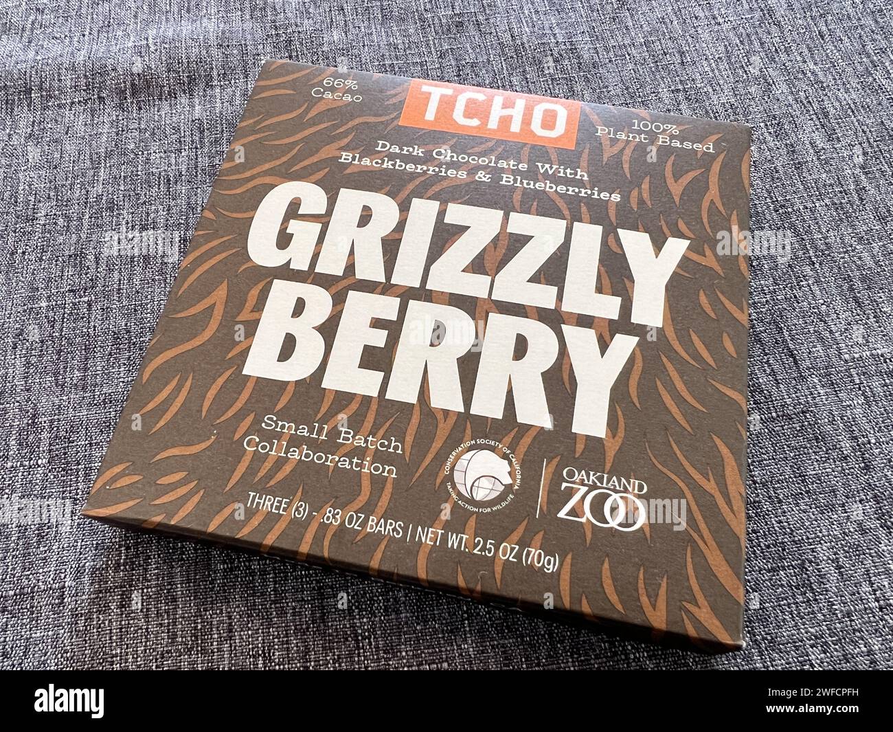 Paket mit TCHO Grizzly Berry dunkler Schokolade mit Brombeeren und Heidelbeeren, hergestellt in Zusammenarbeit mit Oakland Zoo, positioniert auf einem strukturierten grauen Stoff, Reliez Valley, Kalifornien, 21. August 2023. Stockfoto