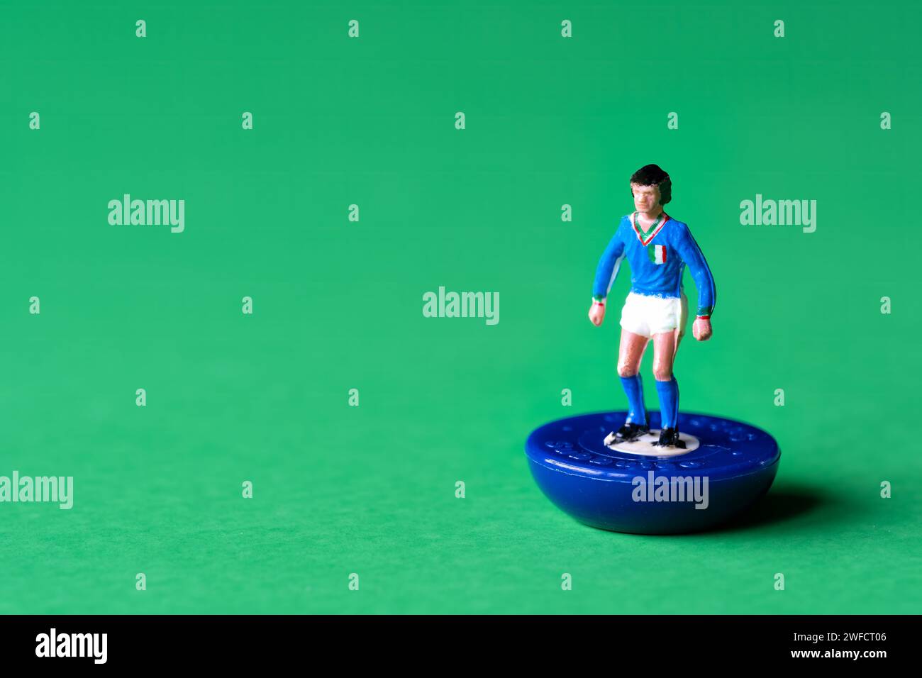 Eine einzelne Subbuteo-Miniaturfigur in den Farben der italienischen Nationalmannschaft, blaues Hemd und weiße Shorts. Subbuteo ist ein Tischfußballspiel Stockfoto