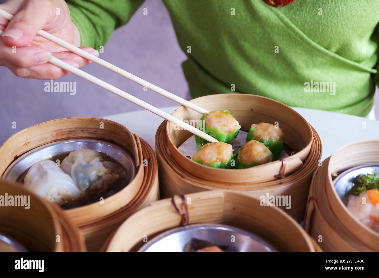 Die Leute schnappen sich einen Shumai, Garnelen und Schweinefleisch gefüllten chinesischen Dumpling mit Essstäbchen Stockfoto