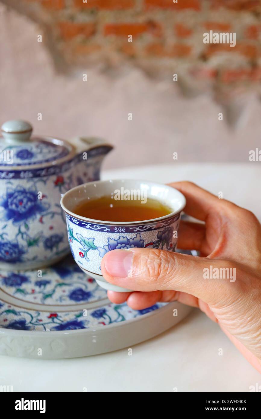 Nahaufnahme einer Hand, die eine Tasse heißen chinesischen Tee hält Stockfoto