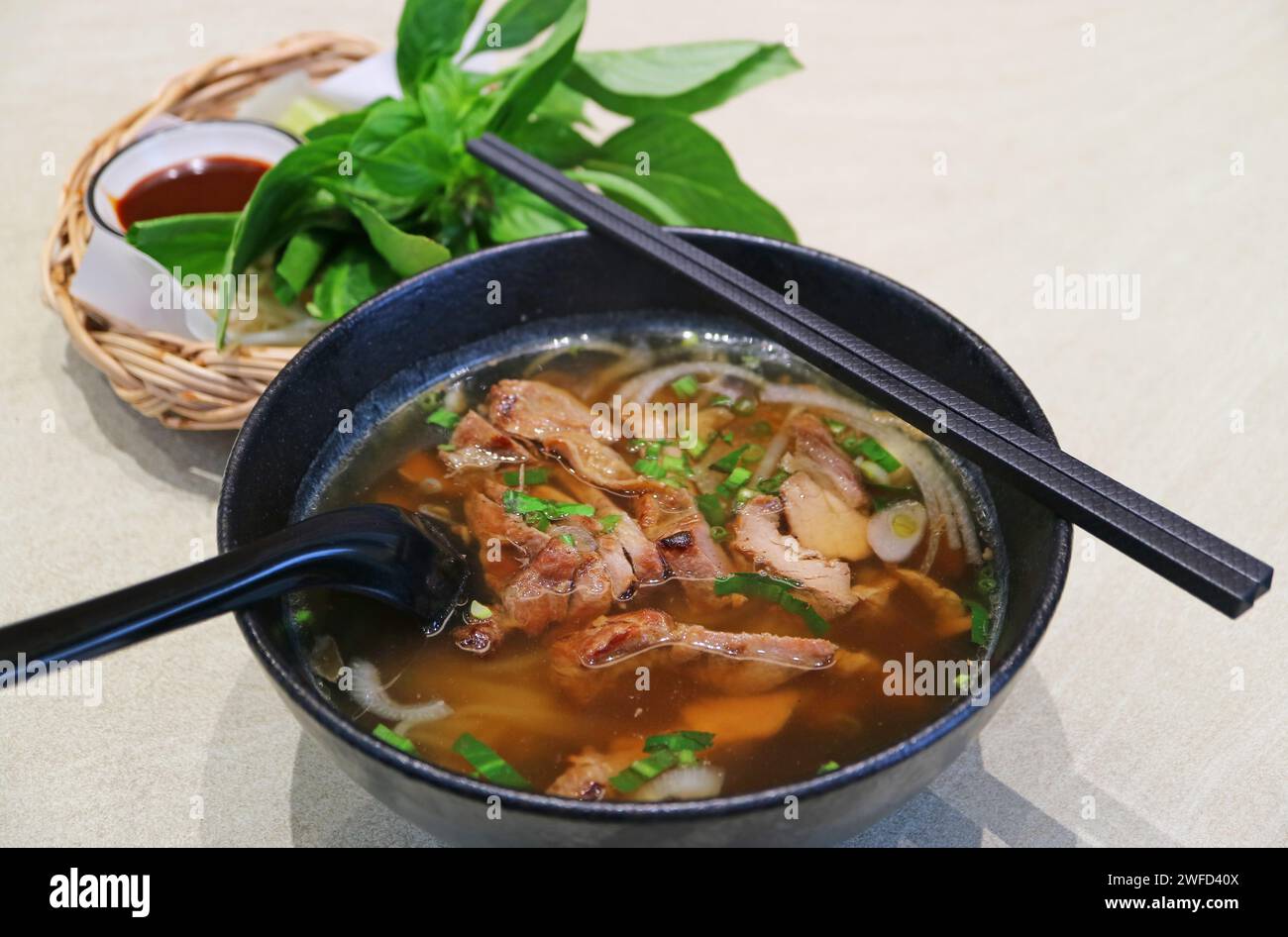 Schüssel mit aromatischem vietnamesischem Pho und gegrilltem Schweinefleisch Stockfoto