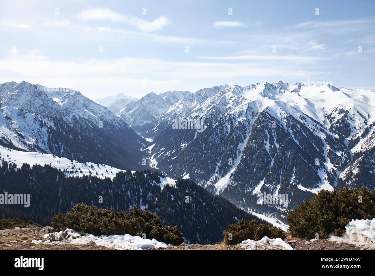 Panoramablick von der Spitze der Hanglage auf schneebedeckte hohe Berge. Winterlandschaft, Bergkette. Karakol Gorge, Skigebiet in Kirgisistan. Stockfoto