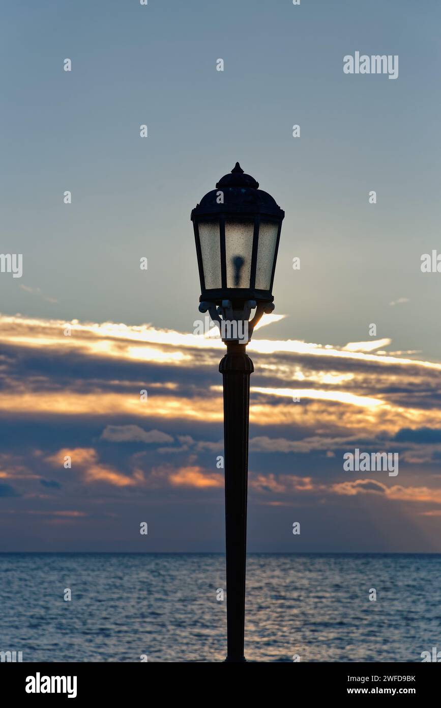 Nahaufnahme eines alten, kunstvollen Lampenpfosten vor einem Winteruntergang in der Abenddämmerung Stockfoto