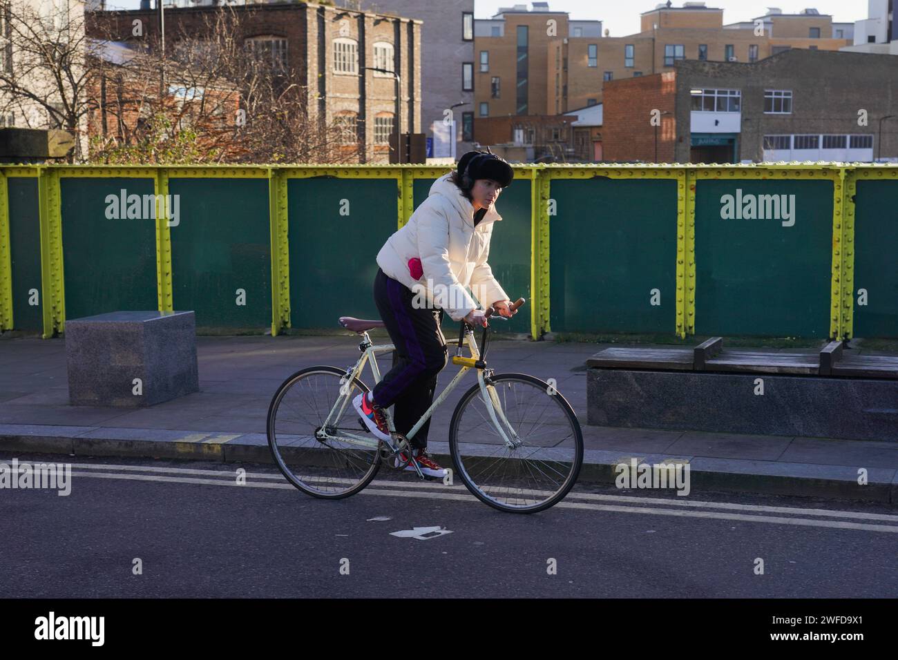 Eine weiße Fahrradfahrerin pendelt in Hackney, East London, in der frühen Morgensonne auf einem weißen Push-Bike. Stockfoto