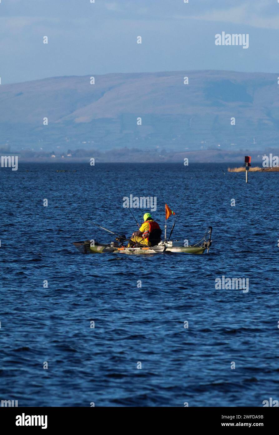 Kinnego, Lough Neagh, County Armagh, Nordirland, Großbritannien. 30. Januar 2024. UK Wetter - nach einem frostigen Start, ein klarer, heller Tag mit Wintersonne, aber kalt in der Brise. Ein Angler, der an einem kalten Wintertag mit den Sperrin Mountains in der Ferne Hecht angeln kann. Quelle: CAZIMB/Alamy Live News. Stockfoto