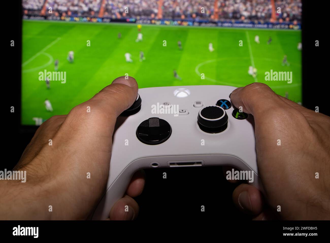 Dnipro, Ukraine, 28. september 2023: Mann spielt EA FC 24 mit Xbox-Controller auf dem TV-Bildschirm. Stockfoto