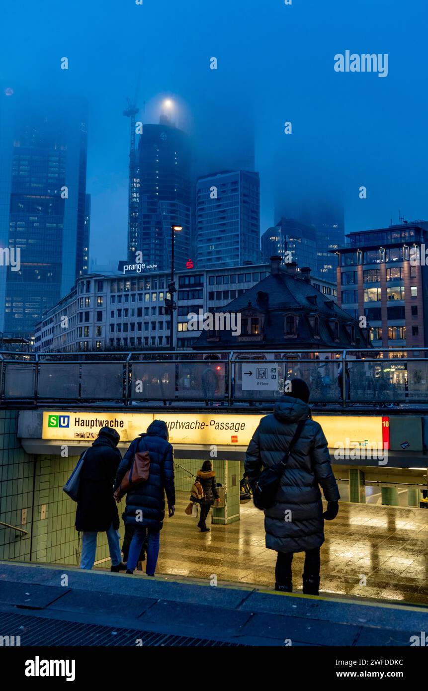 Regnerisches Wetter, eiskalter Regen, Eingang zur U-Bahn-Station Hauptwache, Hochhaus-Skyline in Wolken, Passanten, die durch das feuchte, eiskalte Wetter eilen, F Stockfoto