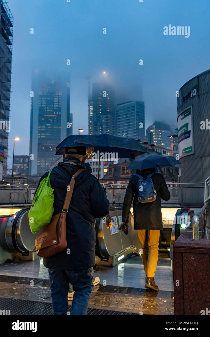 Regnerisches Wetter, eiskalter Regen, Eingang zur U-Bahn-Station Hauptwache, Hochhaus-Skyline in Wolken, Passanten, die durch das feuchte, eiskalte Wetter eilen, F Stockfoto