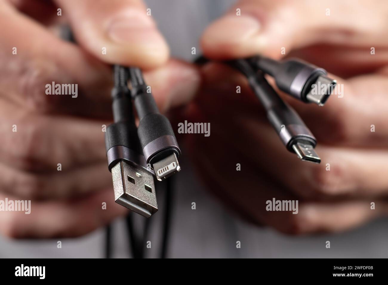 Hände halten das Universal-Adapterkabel von USB-Anschluss zu Micro-USB-, Mini-USB- und anderen Anschlüssen. Stockfoto