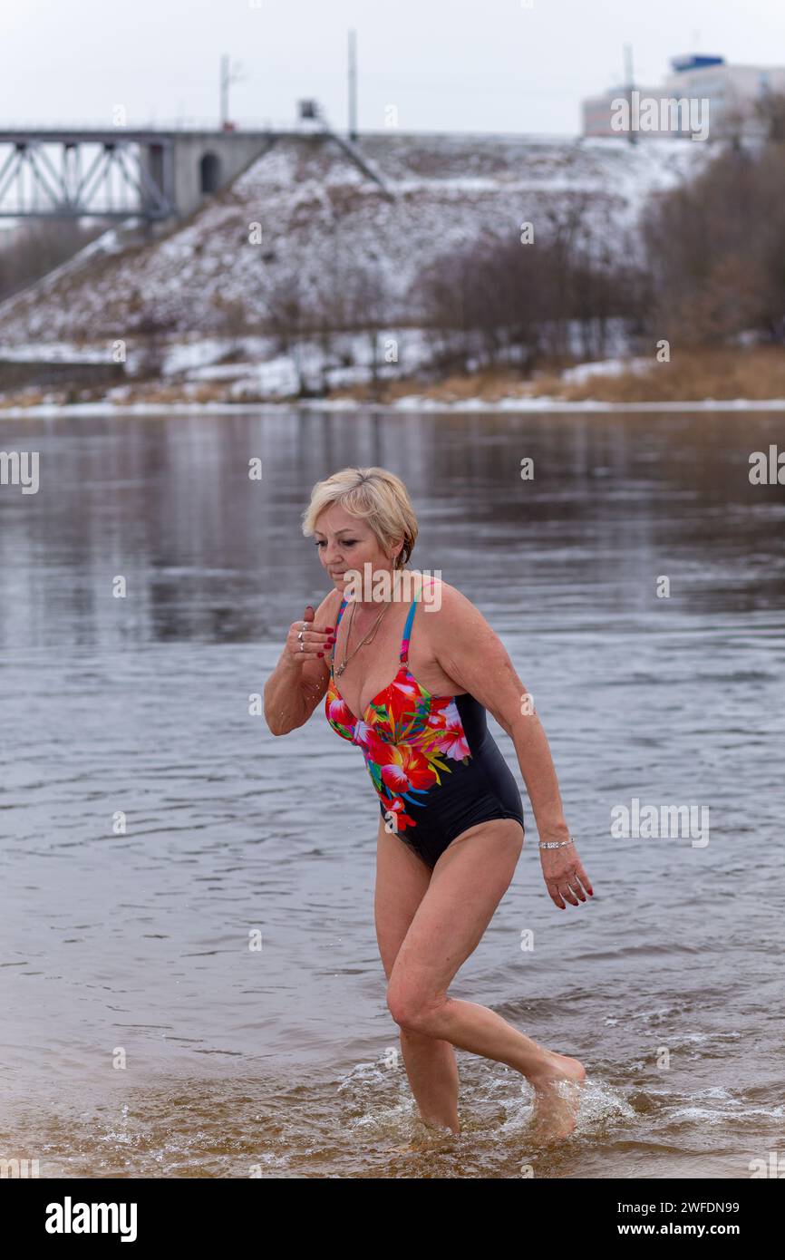 Grodno, Weißrussland - 28. Januar 2024: Eine Erwachsene Frau plätschert im Winter während des traditionellen jährlichen Temper-fest-Rennens im Fluss. Ein Taucherleben Stockfoto