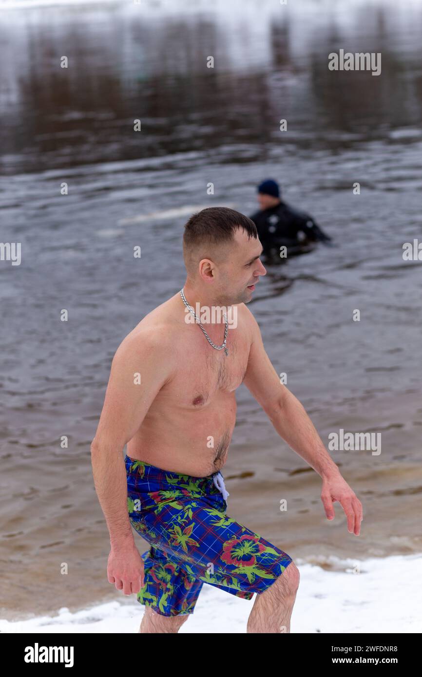 Grodno, Weißrussland - 28. Januar 2024: Junger Mann plätschert im Winter während des traditionellen jährlichen Temper-fest-Rennens im Fluss. Ein Rettungsschwimmer für Taucher Stockfoto