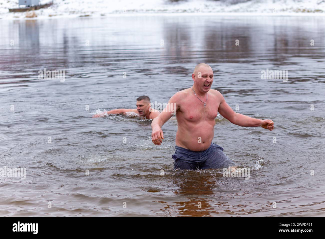 Grodno, Weißrussland - 28. Januar 2024: Junger Mann plätschert im Winter während des traditionellen jährlichen Temper-fest-Rennens im Fluss. Ein Rettungsschwimmer für Taucher Stockfoto