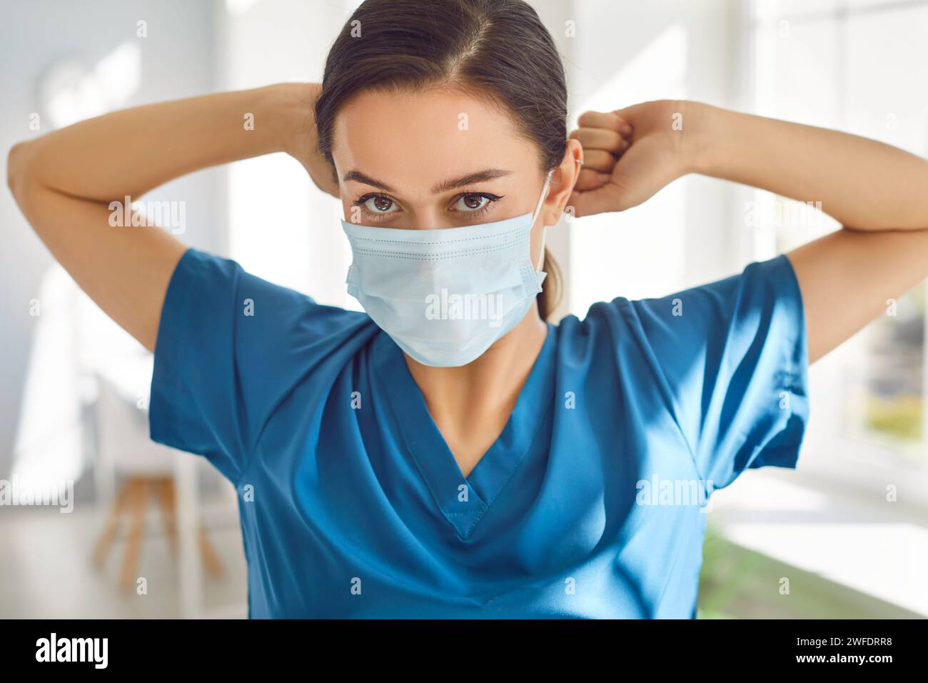 Porträt einer jungen Ärztin mit medizinischer Maske, die in der Klinik in die Kamera blickt. Stockfoto