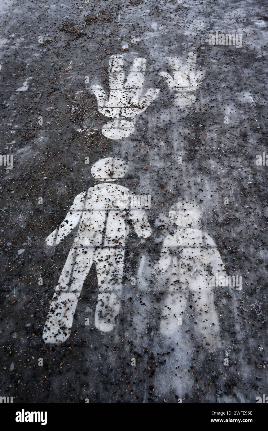 Eisbedeckter Gehweg mit einem Fußgängerschild, das mit Granitsplittern bestreut ist Stockfoto