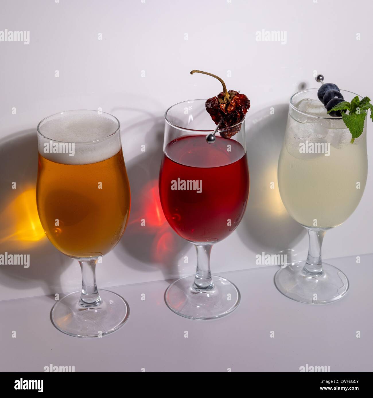 Cocktails und Bier werden im Studio vor weißem Hintergrund zubereitet und garniert Stockfoto