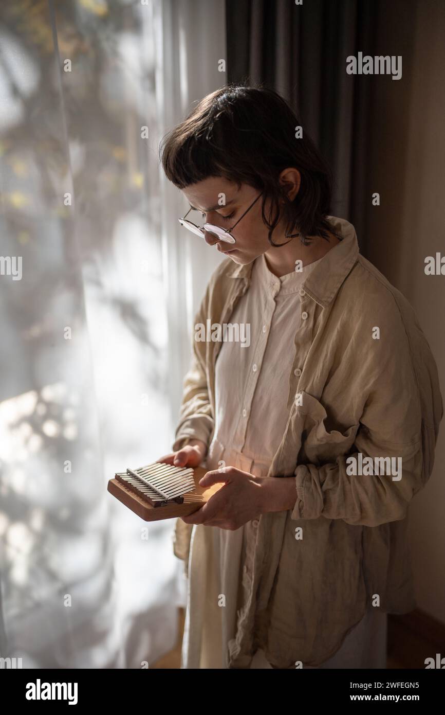 Teenager Mädchen lernten, um Musik auf Kalimba zu spielen, herrliche Klänge zu genießen und zu Hause neben dem Fenster zu stehen Stockfoto