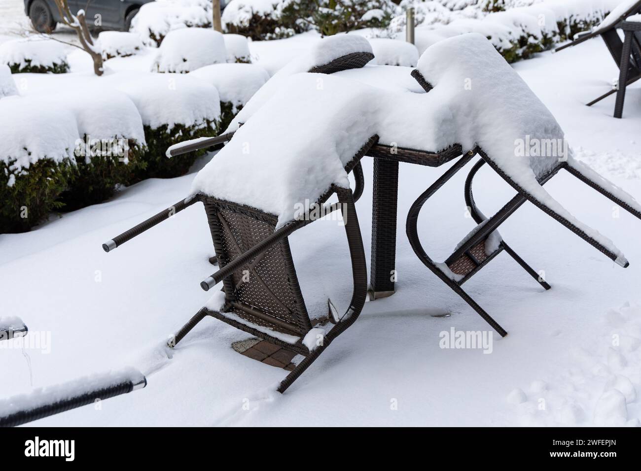 Plastikstühle und ein Gartentisch, bedeckt mit einer dicken Schneeschicht. Ungeschützte Gartenmöbel für den Winter. Stockfoto