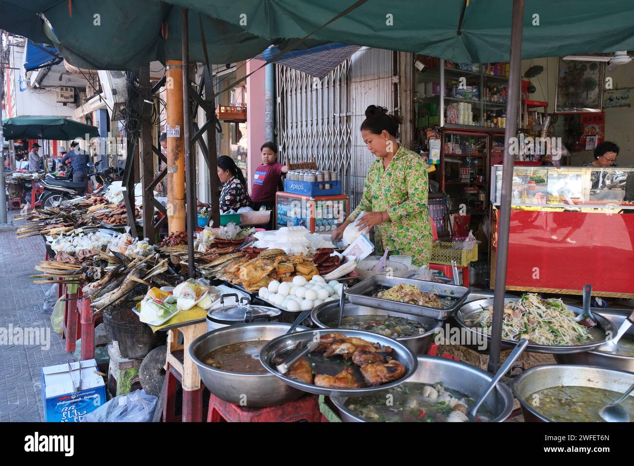 Frau, die Essen und andere billige Sachen auf der Straße in Downtown Phnom Penh, Kambodscha verkauft Stockfoto