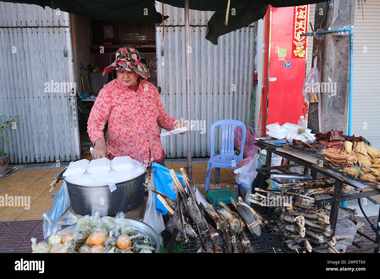 Frau, die Essen und andere billige Sachen auf der Straße in Downtown Phnom Penh, Kambodscha verkauft Stockfoto