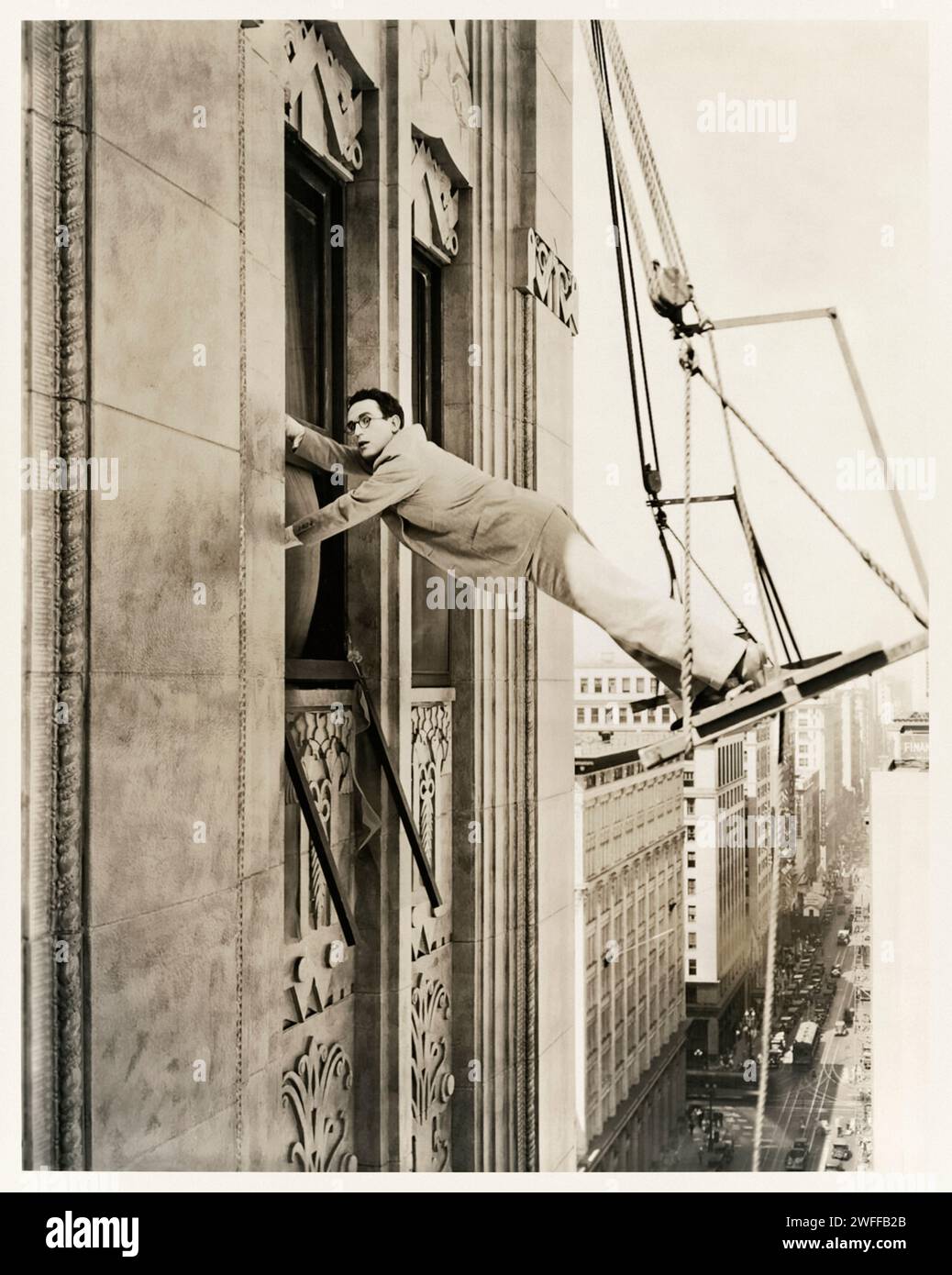 Harold Lloyd balancierte in einer Szene aus „Feet First“, die 1930 von Paramount veröffentlicht wurde, unsicher auf die Wiege eines Malers. Fotografie des Originalfotos aus dem Jahr 1930. Kredit: Private Collection / BFA Stockfoto