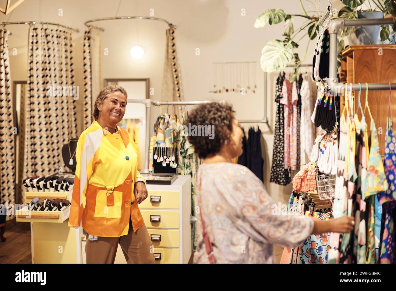 Lächelnde Verkäuferin mit Behinderung, die weibliche Kundin beim Einkaufen im Geschäft ansieht Stockfoto