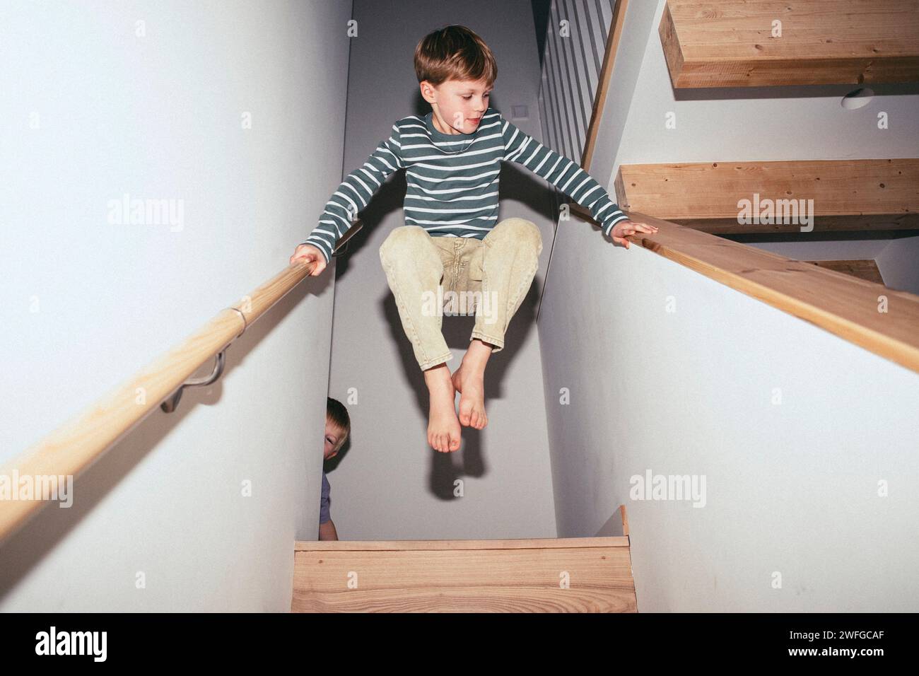 Niedriger Winkel des Jungen, der mitten in der Luft zwischen der Treppe ausbalanciert, während er zu Hause spielt Stockfoto