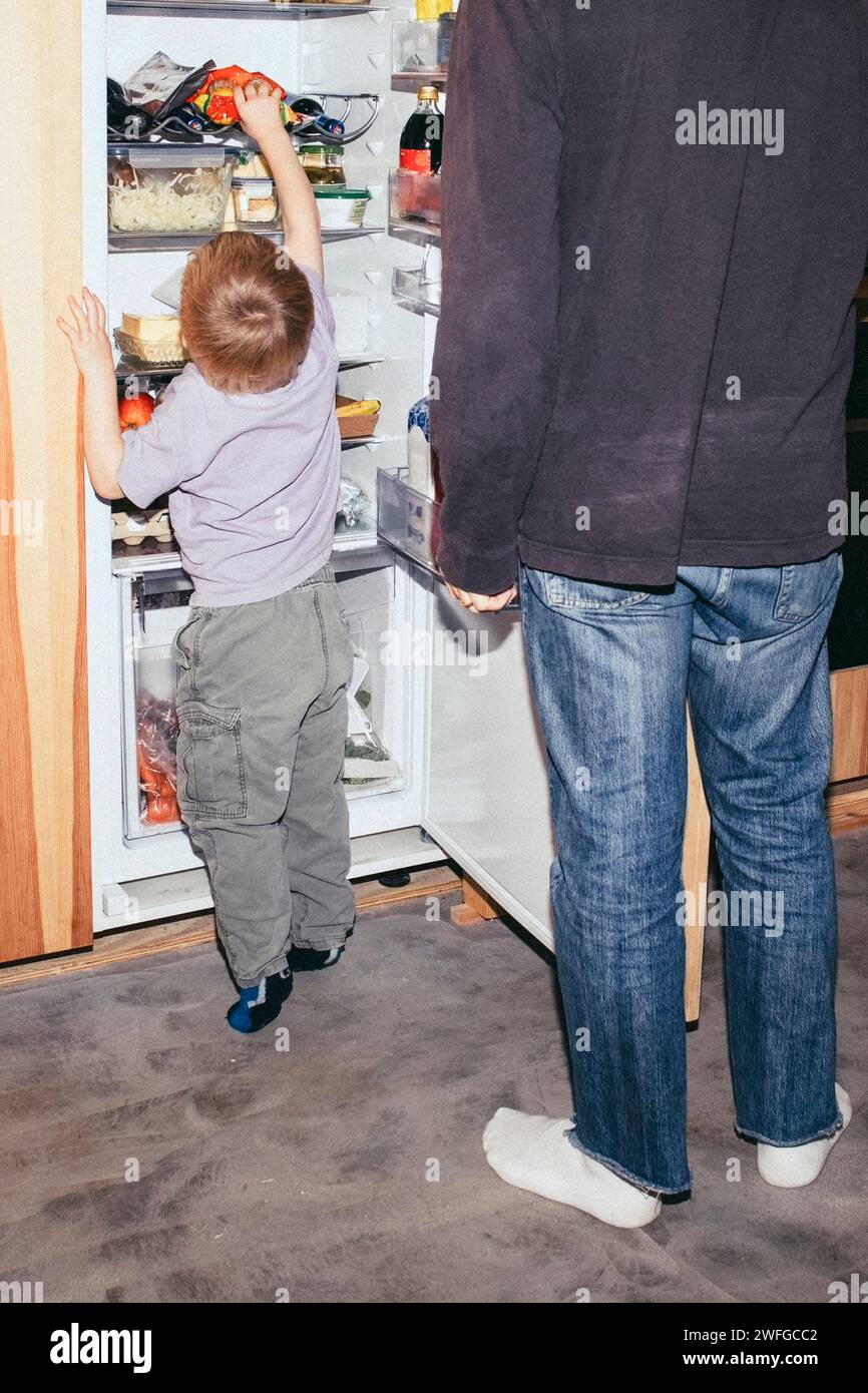 Vater steht mit neugierigem Sohn auf der Suche im Kühlschrank zu Hause Stockfoto