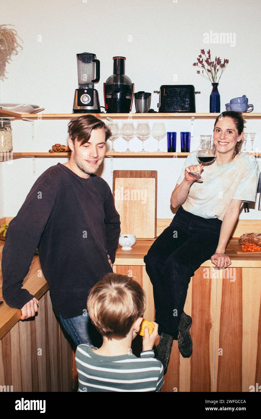 Glückliche Familie, die Essen und Getränke in der Küche zu Hause genießt Stockfoto