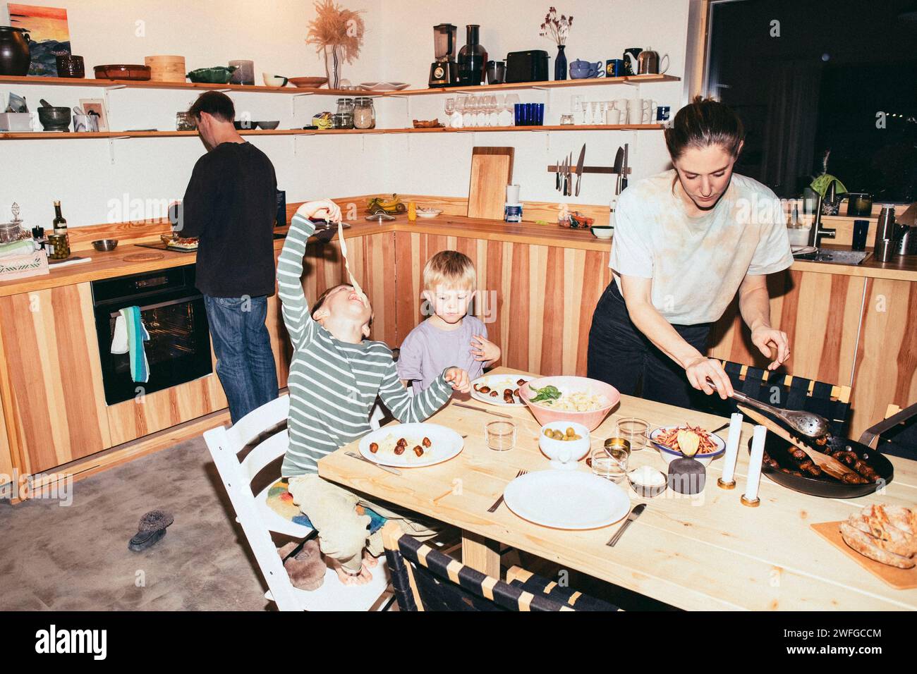 Brüder essen am Esstisch mit Mutter in der Küche Stockfoto