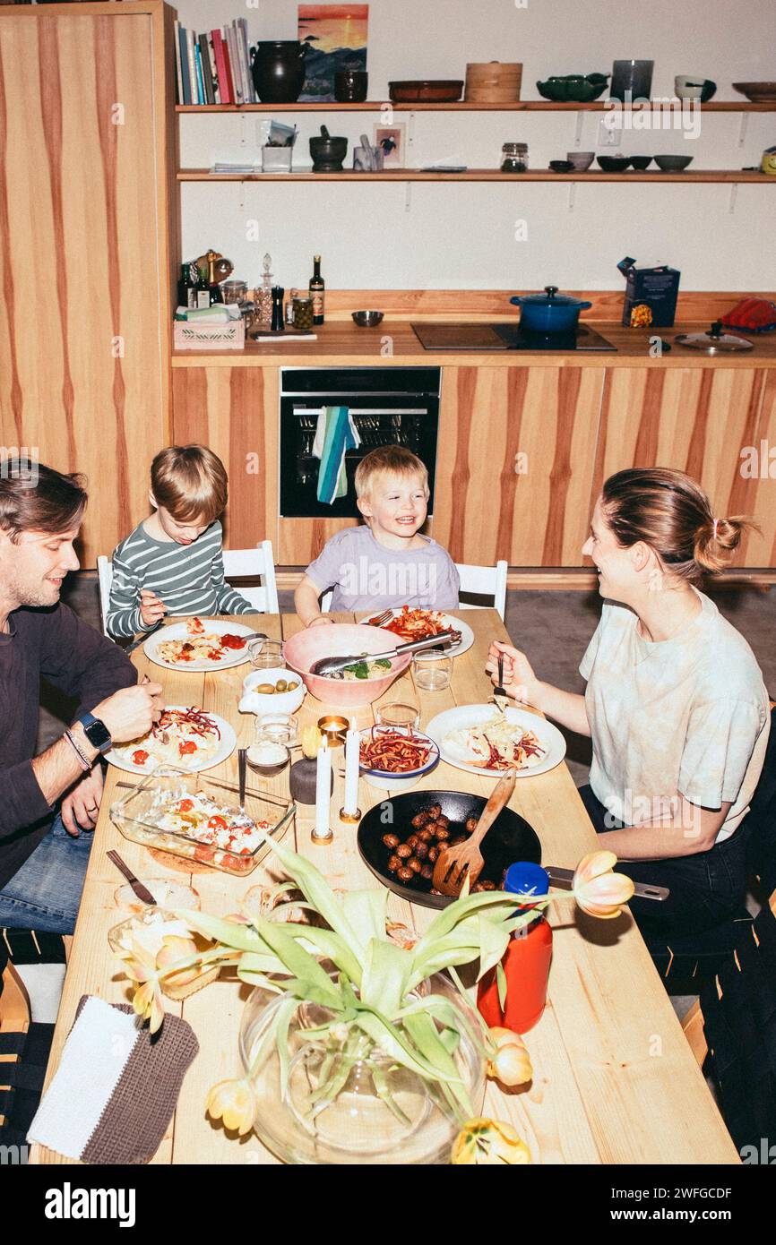 Blick auf die glückliche Familie, die Spaß beim Abendessen am Esstisch in der Küche hat Stockfoto