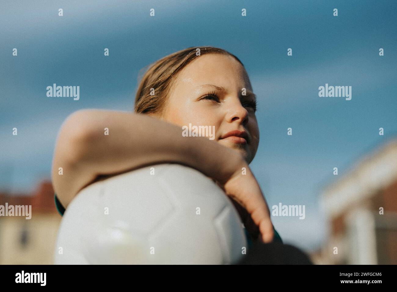 Besinnliches Mädchen mit Sportball, das gegen den Himmel blickt Stockfoto