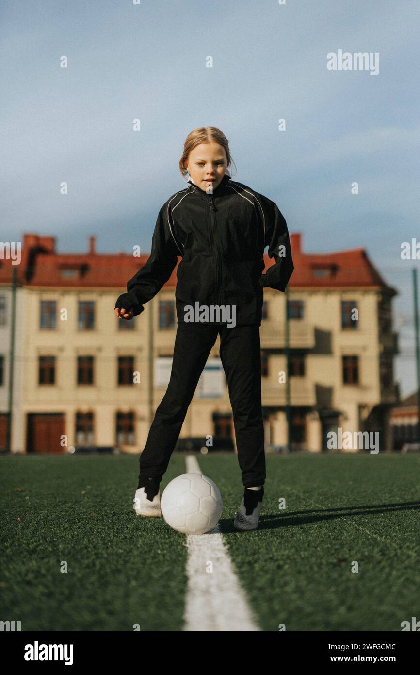 Weibliche Athletin, die mit Fußball gegen den Himmel auf dem Sportplatz spielt Stockfoto