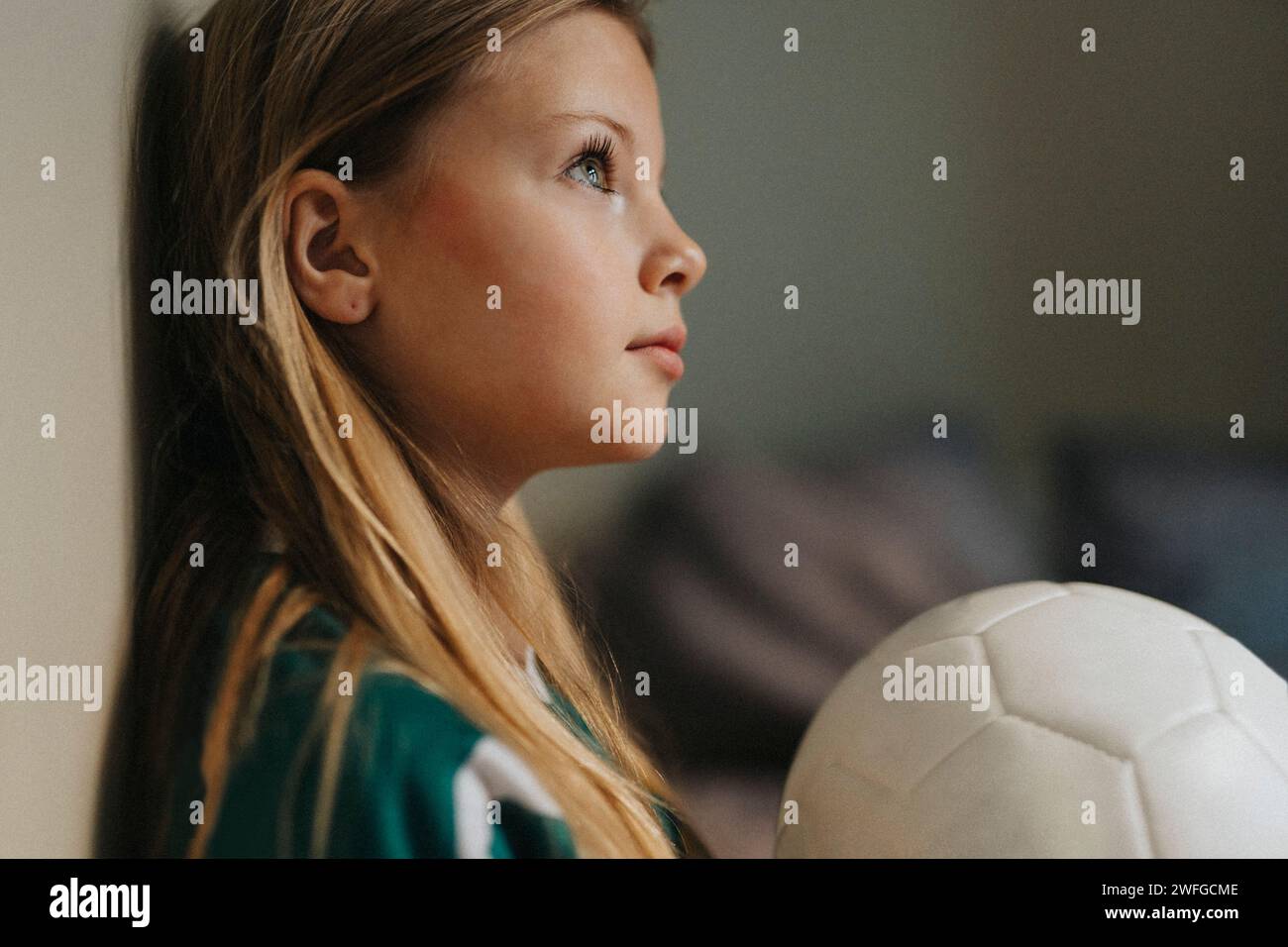 Besinnliches Mädchen mit Sportball, das nach Hause blickt Stockfoto
