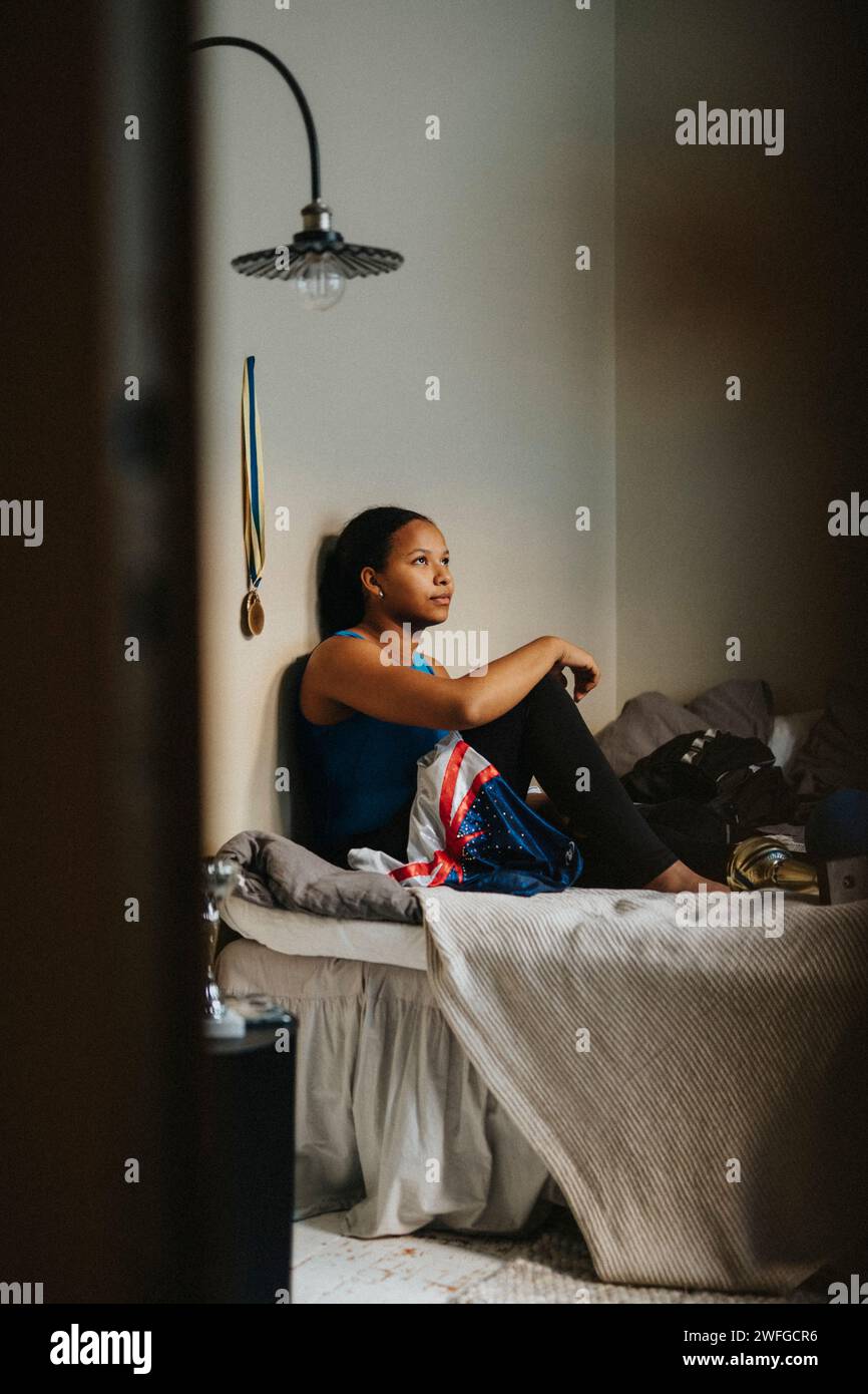 Teenager-Mädchen, das zu Hause im Schlafzimmer an der Wand sitzt Stockfoto